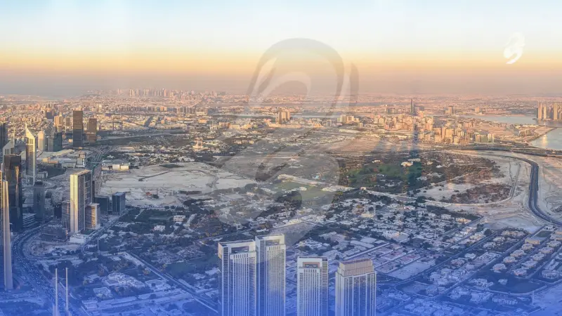 High-altitude aerial view of an extensive urban metropolis and desert city skyline during golden hour, featuring high-rise towers, sprawling suburban neighborhoods, and distant infrastructure under a warm sunset sky.